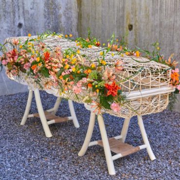Wilgenmand met bloemen als alternatief voor een houten kist
